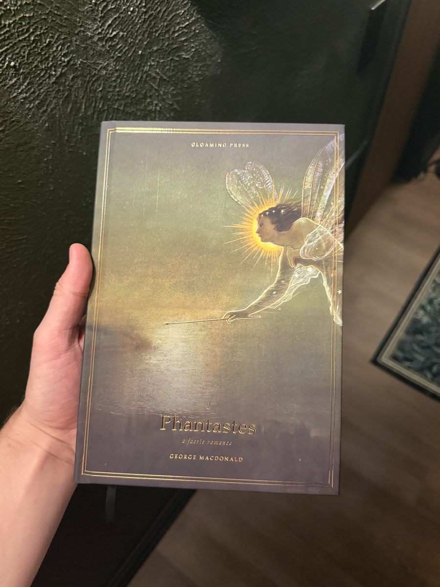 The edition held up against a dark wall, the fairy glowing on the cover